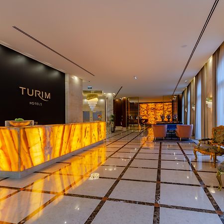 Turim Boulevard Hotel (Adults Only) Lisbona Esterno foto The image shows the interior of a hotel lobby. The design features a modern and elegant style, with a prominent reception desk illuminated by warm lighting, likely made of stone or a similar material, displaying the name "TURIM HOTELS" prominently. T
