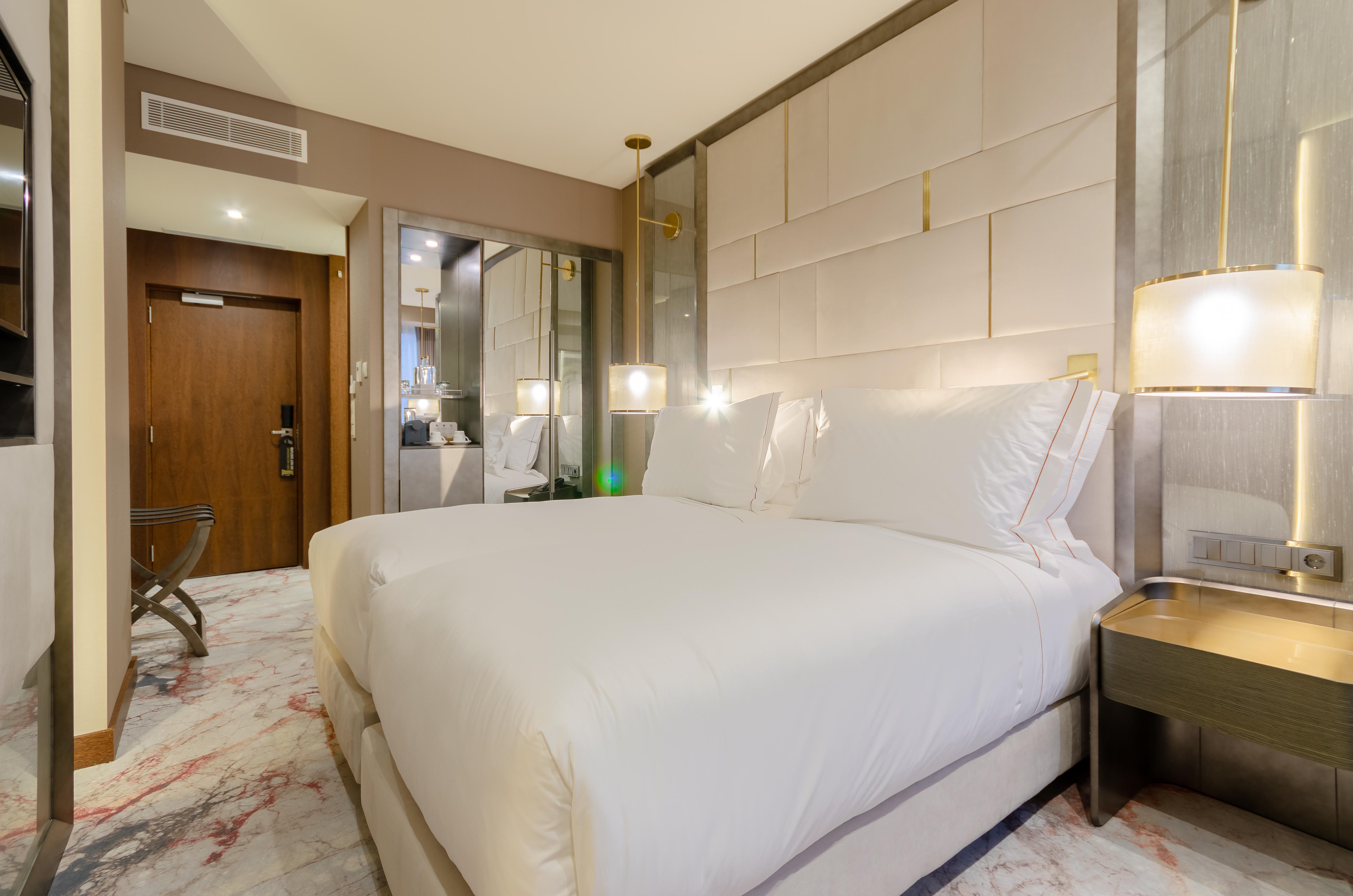Turim Boulevard Hotel (Adults Only) Lisbona Esterno foto The photo shows an elegantly designed hotel room featuring two neatly made beds with white linens. The room has a modern aesthetic, with soft lighting provided by bedside lamps. There’s a stylish nightstand beside each bed, and the floor is adorned w