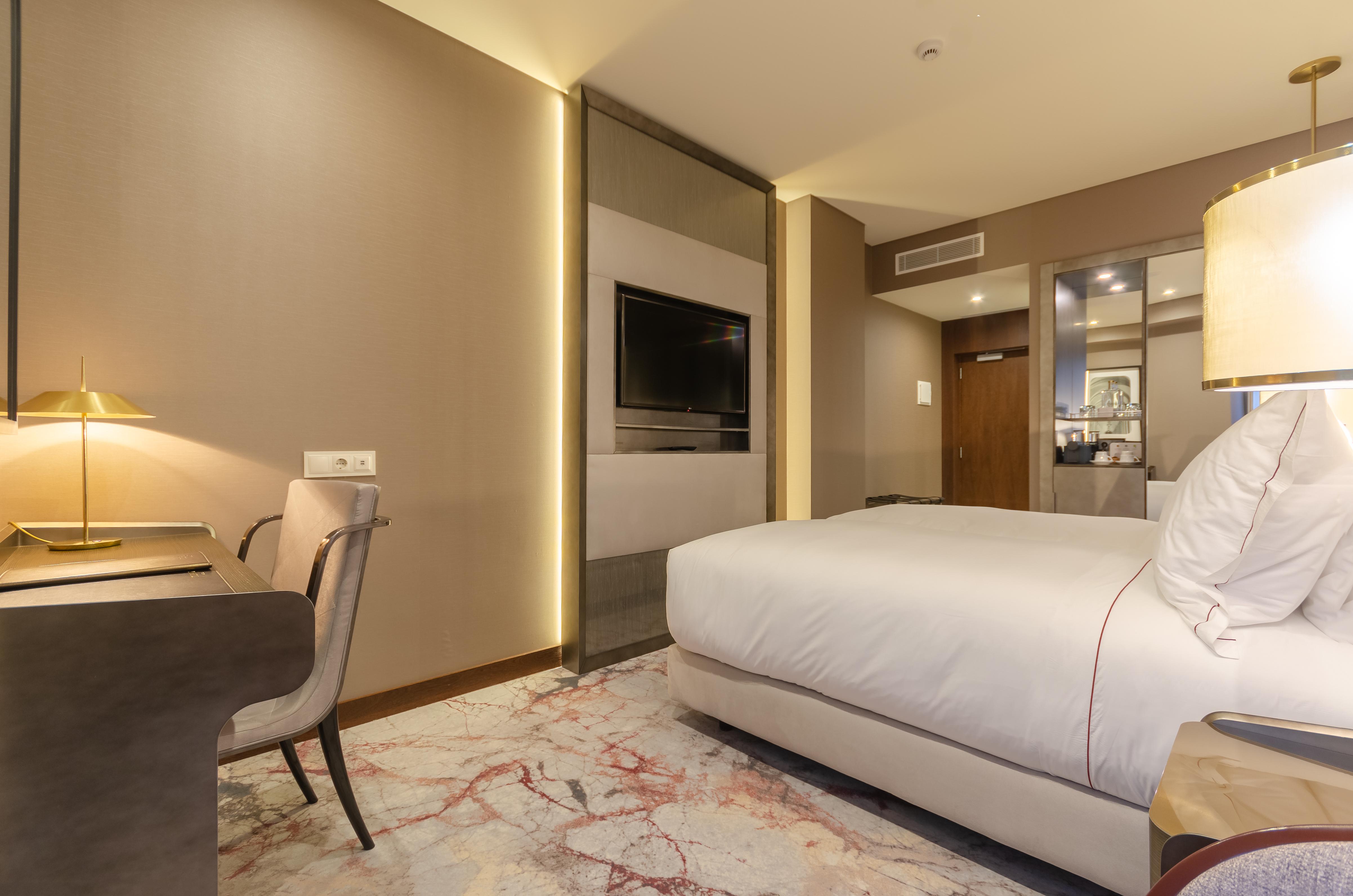 Turim Boulevard Hotel (Adults Only) Lisbona Esterno foto The photo shows a modern hotel room with a contemporary design. It features a large bed with white linens, positioned against a wall. Next to the bed, there is a stylish lamp. A sleek desk and chair are located in the corner, providing a workspace. 
