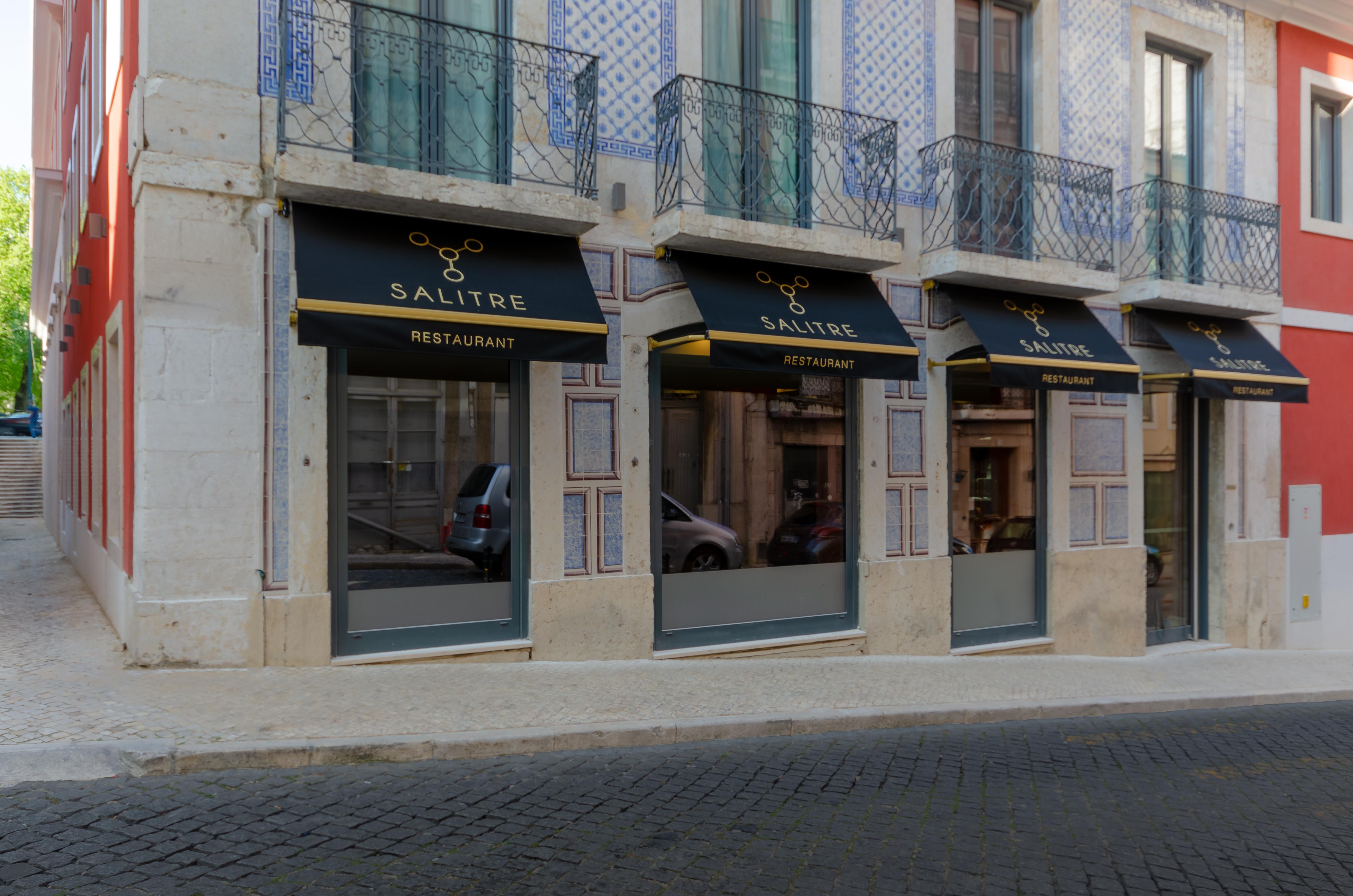 Turim Boulevard Hotel (Adults Only) Lisbona Esterno foto The photo shows the exterior of a restaurant named "SALTRE." The restaurant has a modern facade with large glass windows. There are black awnings above the windows that feature the restaurant's name in gold lettering. The building appears to have a m