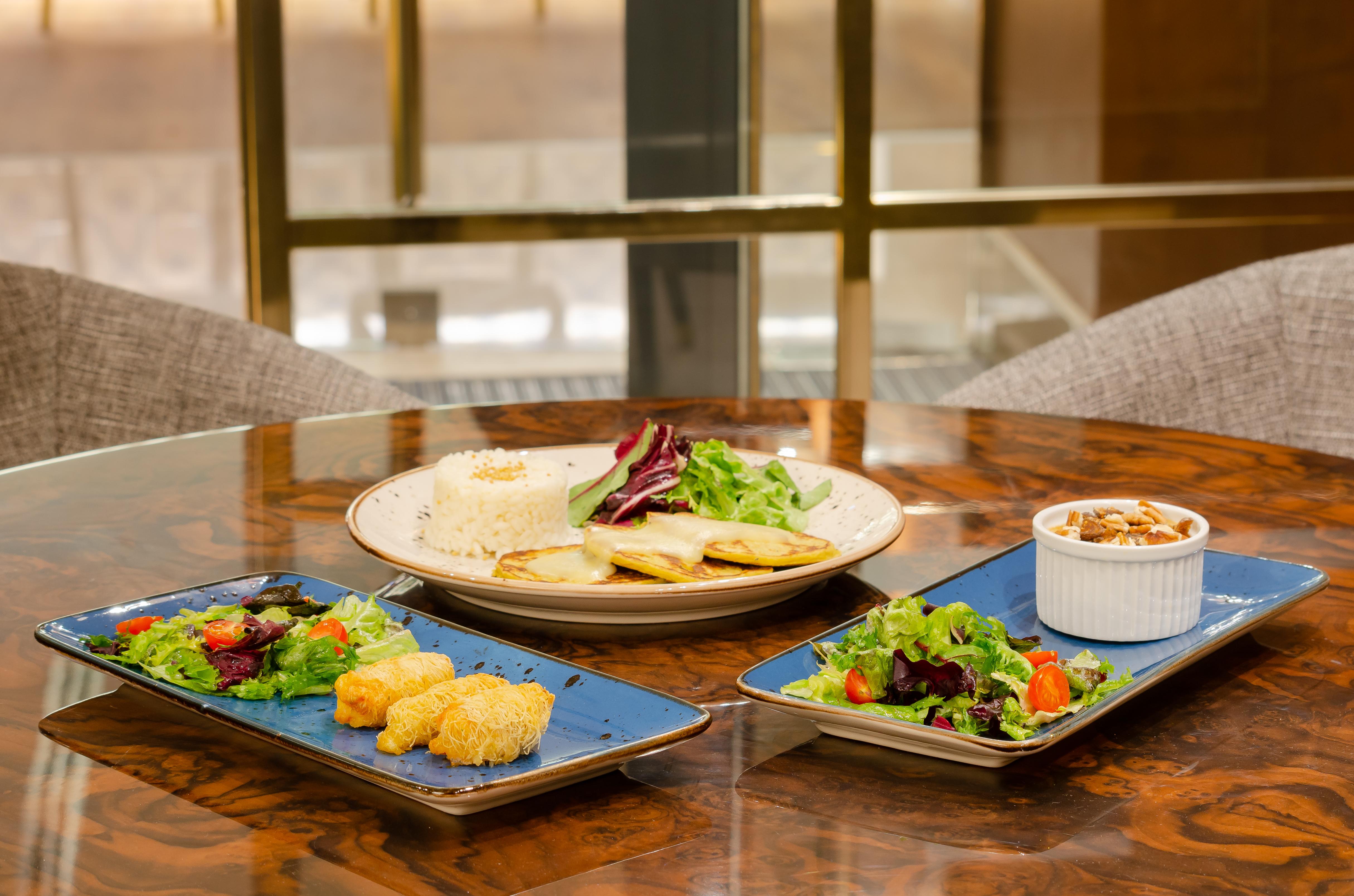 Turim Boulevard Hotel (Adults Only) Lisbona Esterno foto The photo shows a beautifully arranged meal on a wooden table. There are three plates:

1. **Main Plate**: In the center, there is a round plate with what appears to be rice, garnished with greens.

2. **Side Plates**: On either side, there are two r