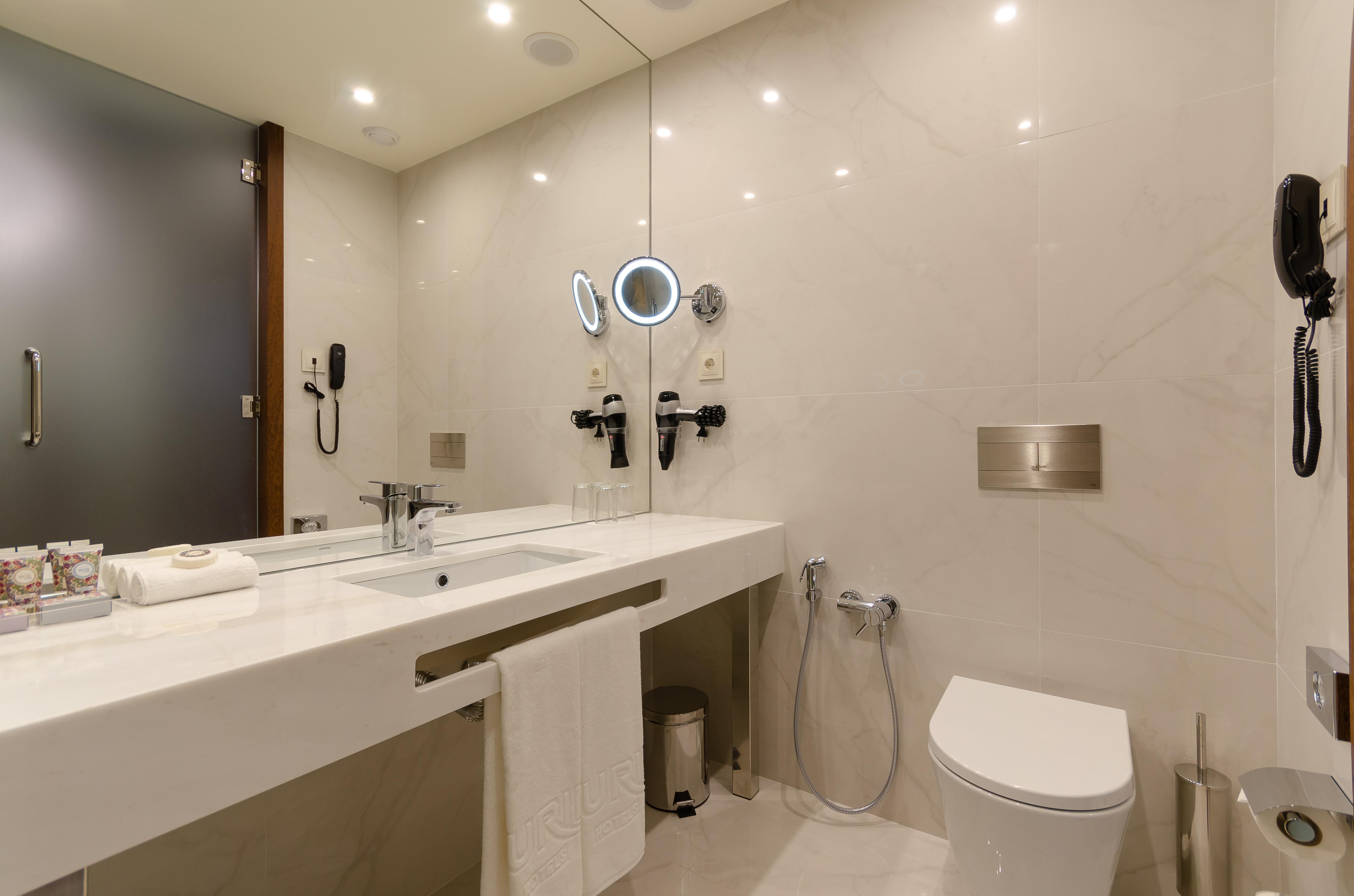 Turim Boulevard Hotel (Adults Only) Lisbona Esterno foto The photo depicts a modern bathroom featuring a sleek and minimalist design. The walls and surfaces are finished in light-colored marble or tiles, creating a clean aesthetic. 

Key elements include:

- A large double sink with a polished countertop a