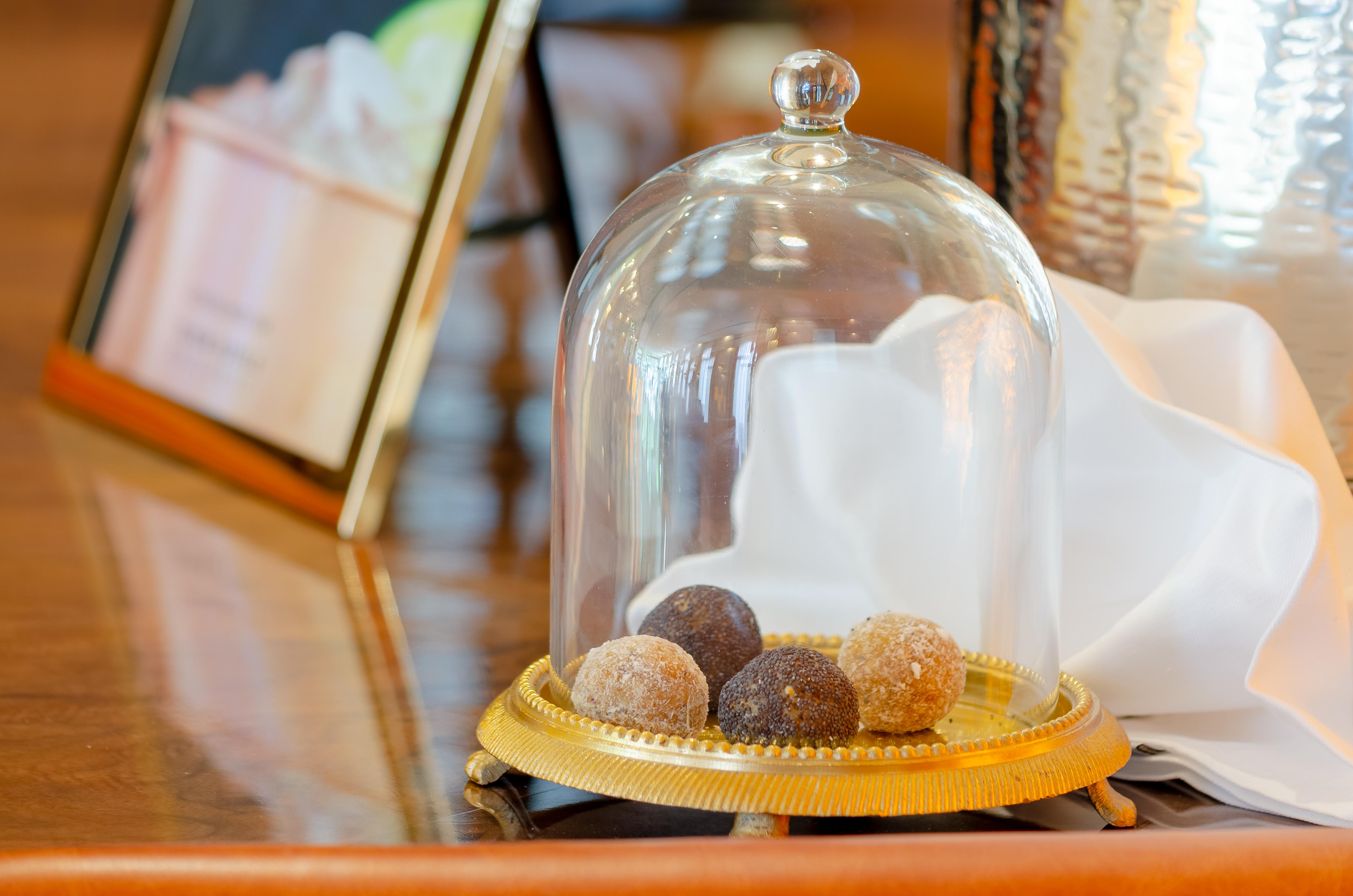 Turim Boulevard Hotel (Adults Only) Lisbona Esterno foto The photo shows a display of truffles or small confections under a glass dome. There are four round treats sitting on a golden plate, varying in color from dark brown to light brown and possibly white. The setting appears elegant, with a folded white