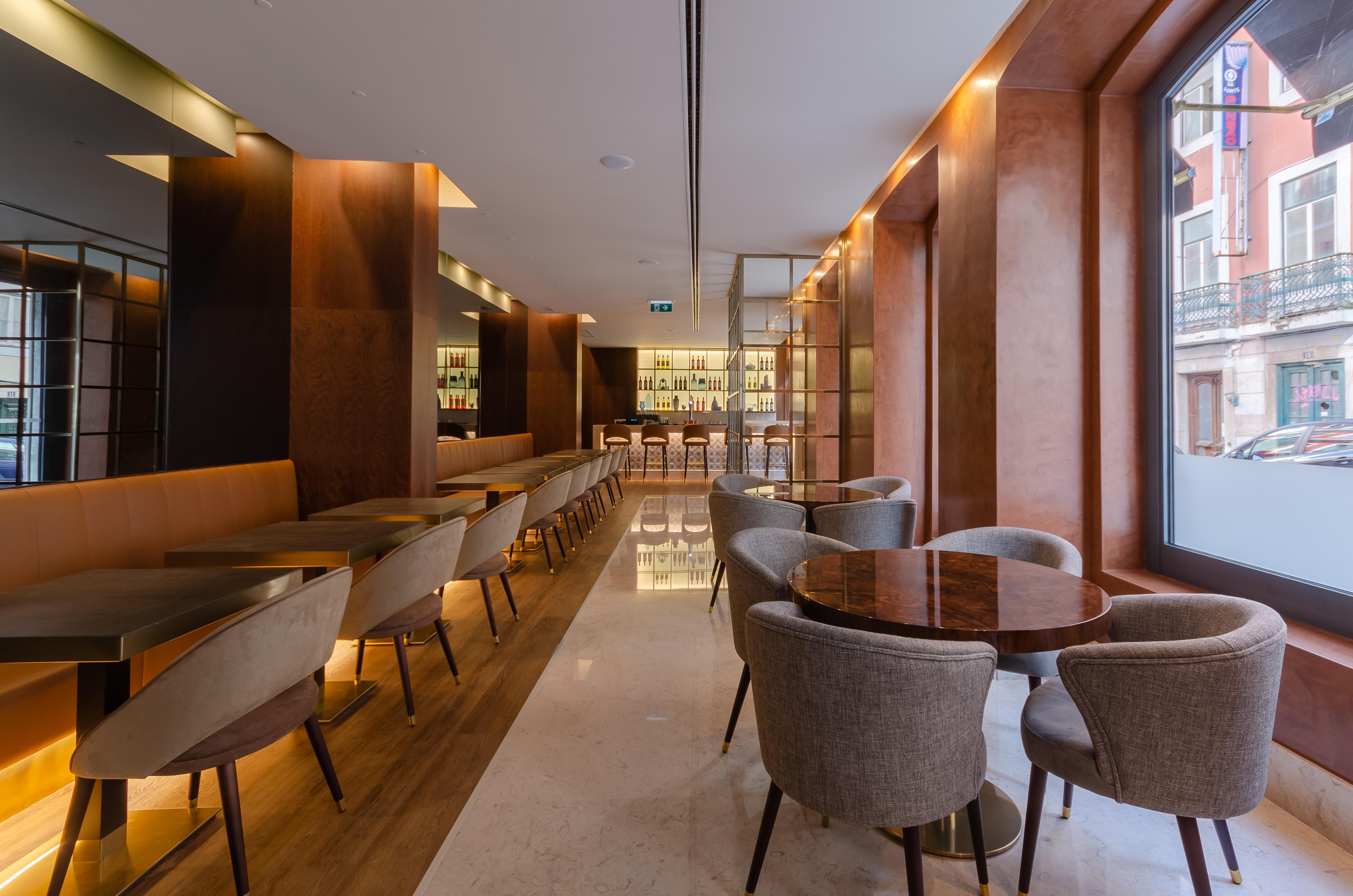 Turim Boulevard Hotel (Adults Only) Lisbona Esterno foto The photo shows the interior of a modern café or restaurant. It features a sleek and stylish design with wooden accents and warm lighting. On the left, there are long, low tables with seating along the side, while towards the center, there are round 