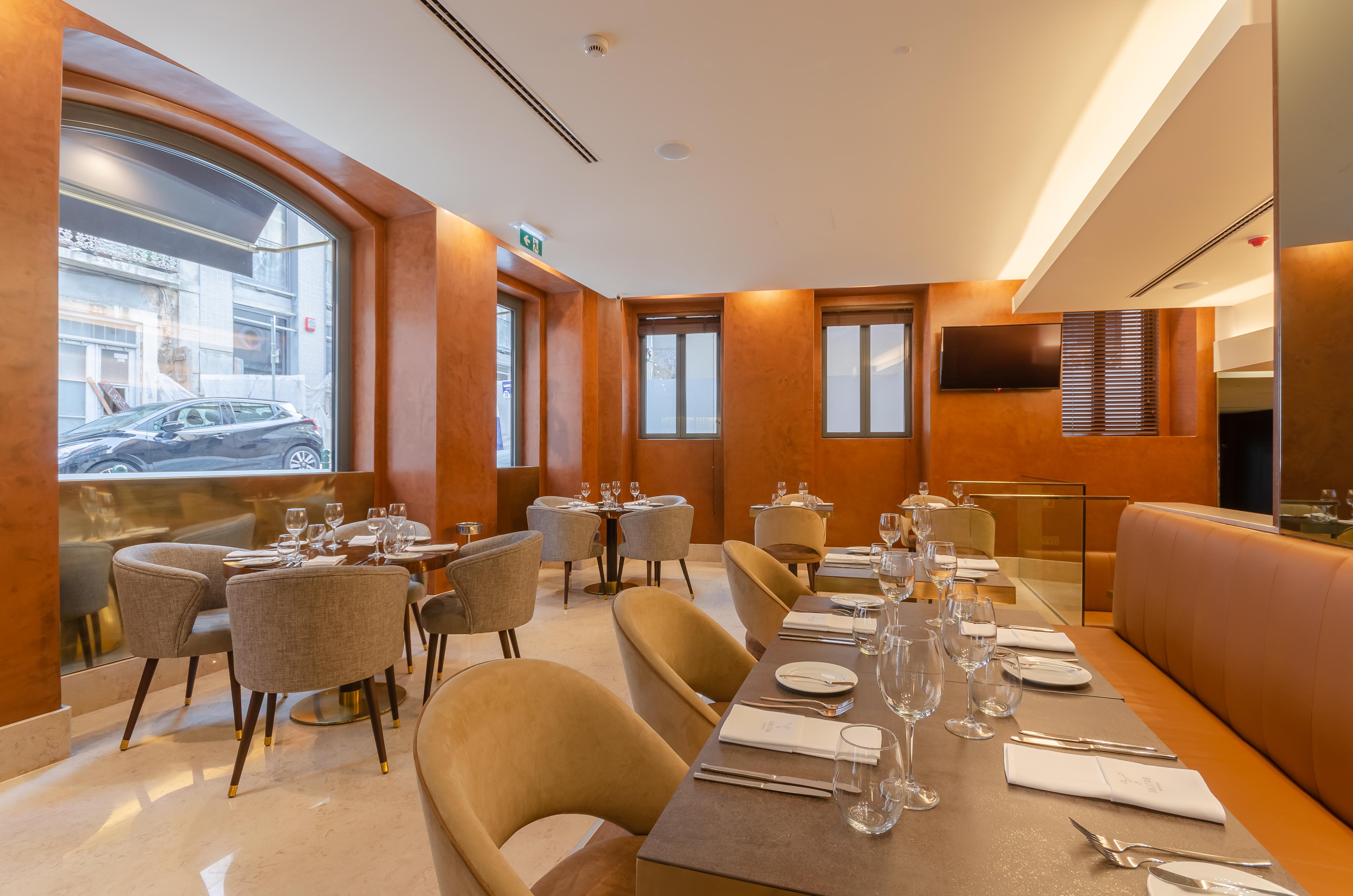 Turim Boulevard Hotel (Adults Only) Lisbona Esterno foto The photo shows an elegant restaurant interior. There are several dining tables set with plates, cutlery, and glassware, indicating a fine dining atmosphere. The walls have a warm, orange hue, and large windows allow natural light to fill the space. 