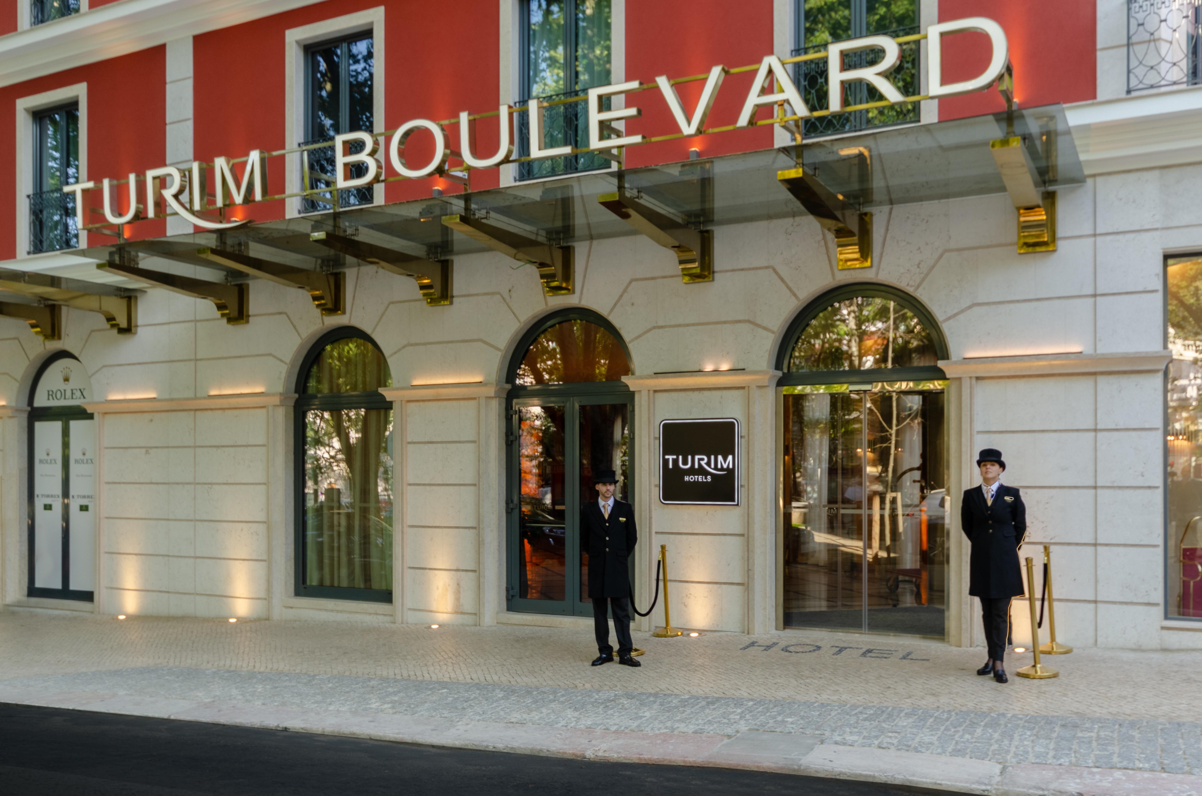 Turim Boulevard Hotel (Adults Only) Lisbona Esterno foto The photo shows the entrance of a hotel called "TURIM Boulevard." The facade features a combination of red and white colors, with large windows and an awning overhead. Two doormen in dark suits are standing at the entrance, adding a touch of elegance