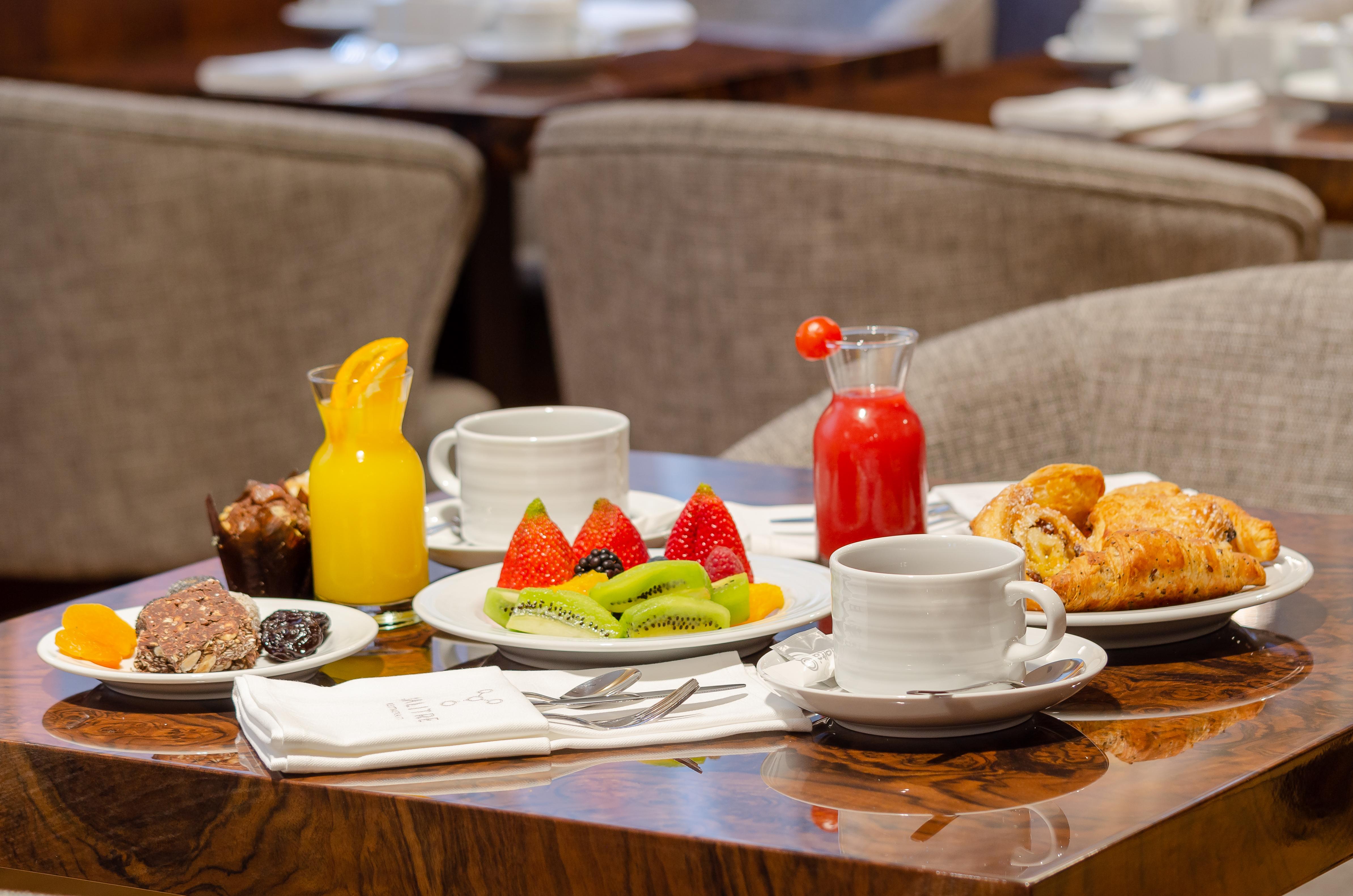 Turim Boulevard Hotel (Adults Only) Lisbona Esterno foto The photo displays a beautifully arranged breakfast or brunch setting. On a wooden table, there are several items including:

- Two cups with saucers, likely for coffee or tea.
- A glass of orange juice or a similar drink.
- A small pitcher of a red 