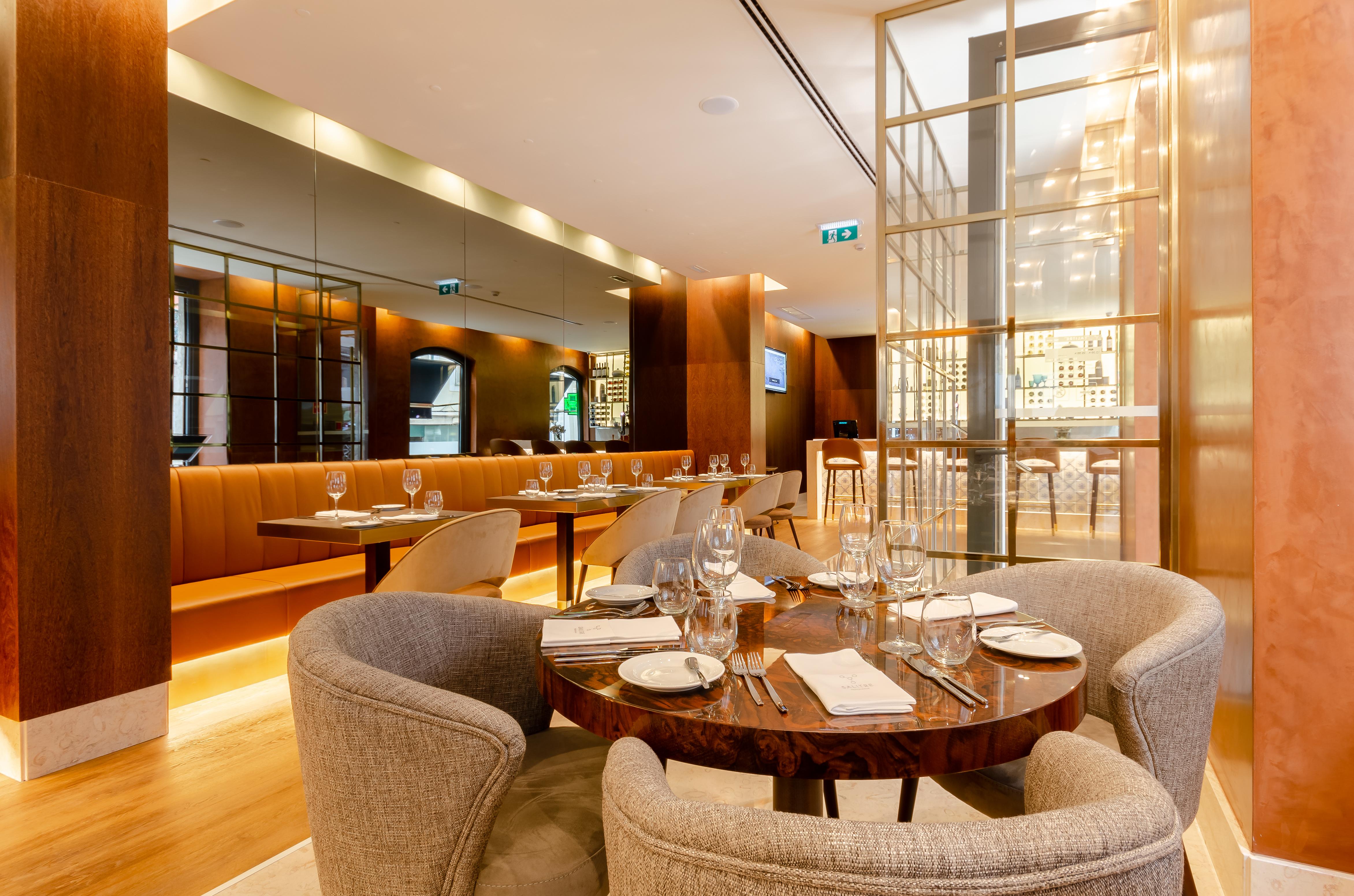 Turim Boulevard Hotel (Adults Only) Lisbona Esterno foto The photo shows a modern and upscale restaurant interior. It features a spacious layout with wooden accents and soft lighting. There are elegant round tables set with white plates and glassware, suggesting a fine dining atmosphere. The seating includ