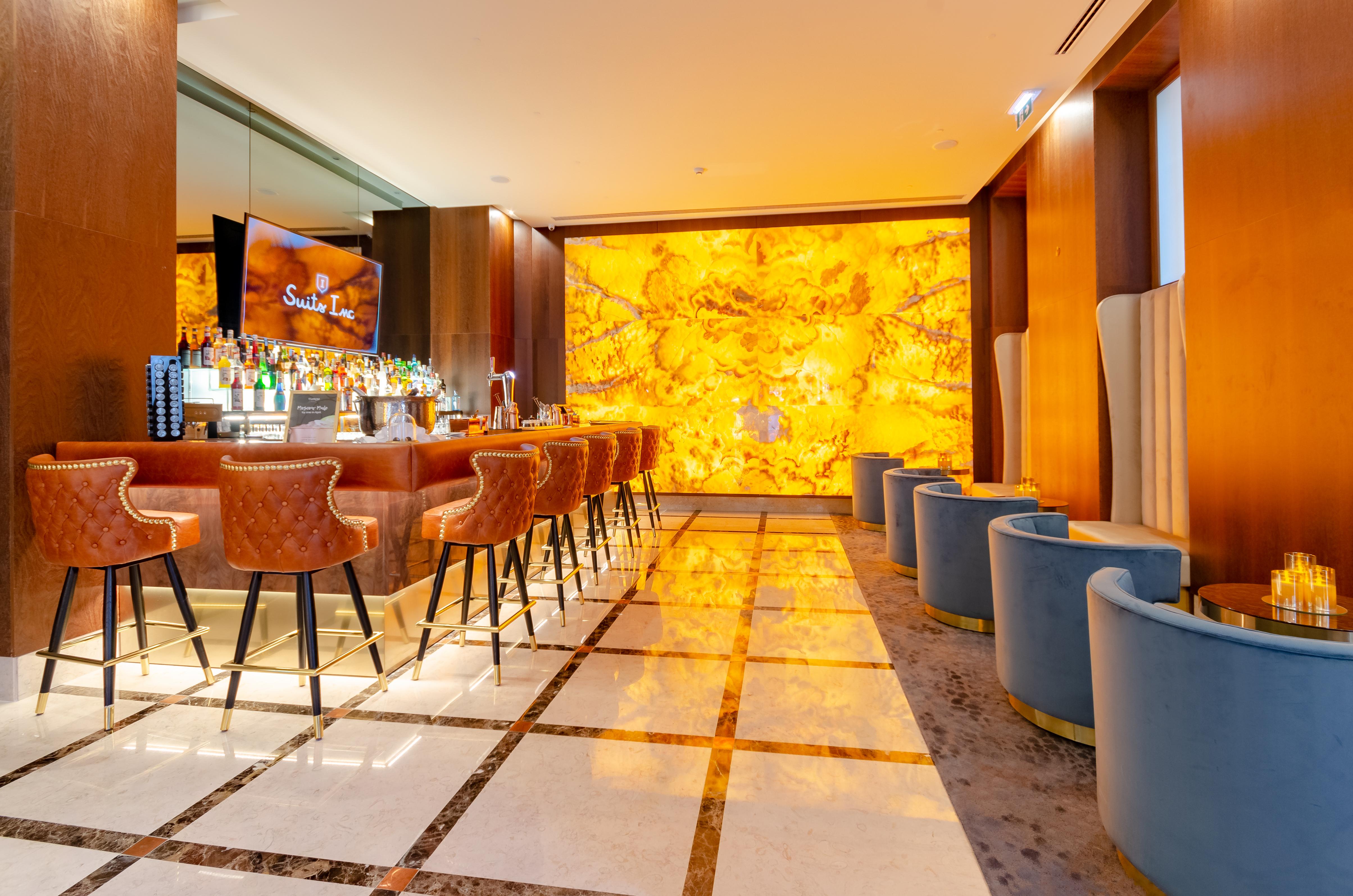 Turim Boulevard Hotel (Adults Only) Lisbona Esterno foto The photo depicts a stylish and modern bar area. In the foreground, there is a polished marble floor with a geometric pattern. The bar itself is made of dark wood and features several high stools with brown upholstery. Behind the bar, a shelf display
