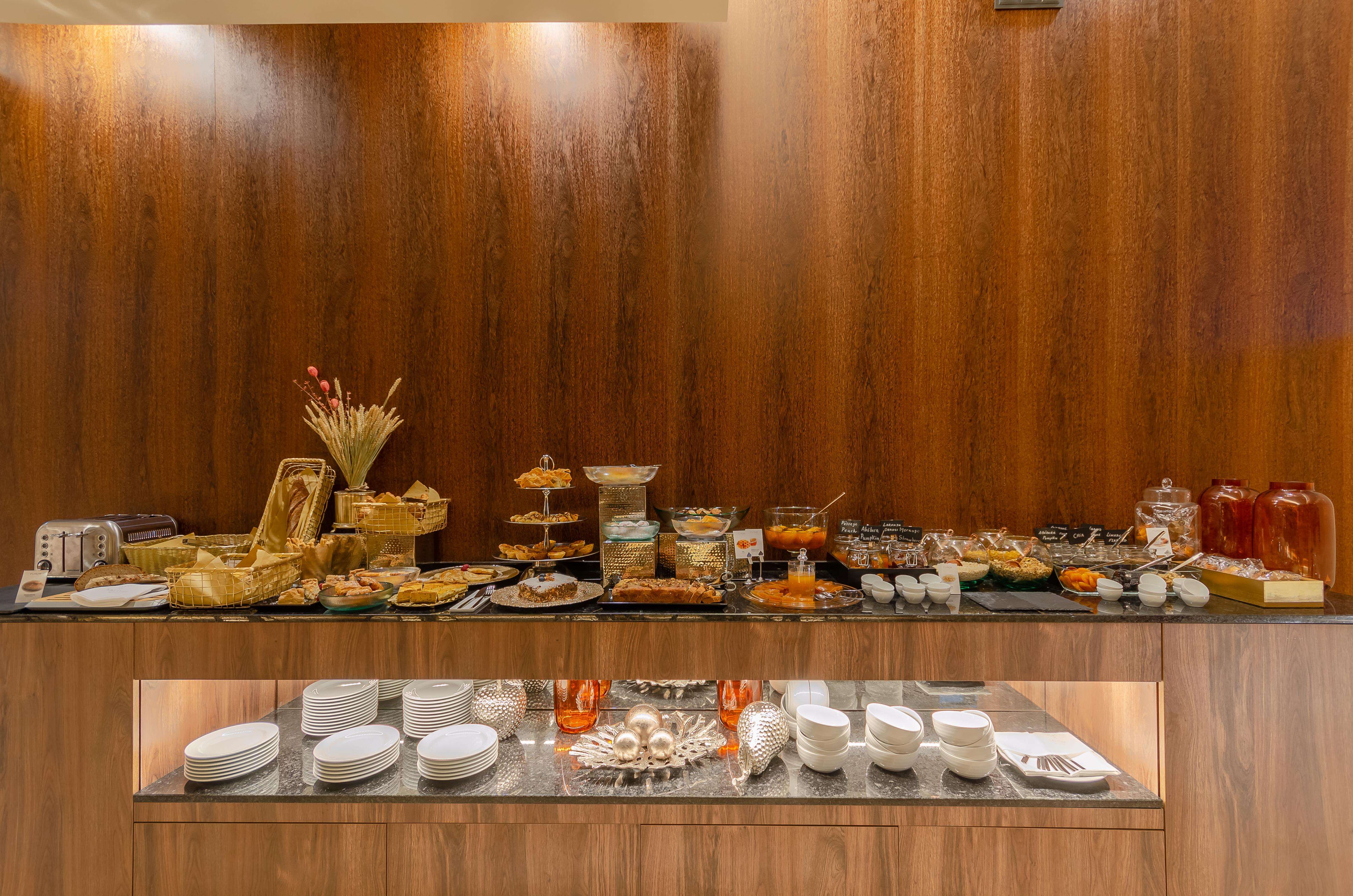 Turim Boulevard Hotel (Adults Only) Lisbona Esterno foto The photo shows a beautifully arranged buffet table featuring a variety of dishes and food items. The table is set against a wooden background and displays multiple trays and bowls filled with different foods. There are desserts, pastries, and savory