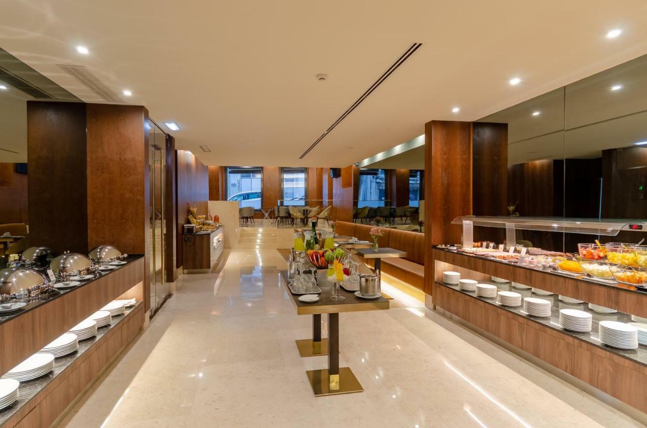 Turim Boulevard Hotel (Adults Only) Lisbona Esterno foto The image shows a modern and elegantly designed dining area, likely a hotel breakfast buffet. The space features a polished floor and warm wooden cabinetry. There are several buffet stations lined along the walls with a variety of food items displaye