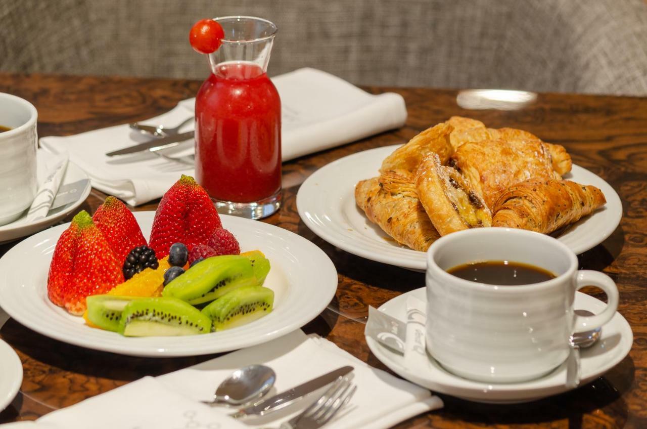 Turim Boulevard Hotel (Adults Only) Lisbona Esterno foto The photo displays a breakfast setting featuring a variety of items. On one plate, there is an assortment of fresh fruit, including strawberries, kiwi, pineapple, and blackberries. Another plate contains a serving of flaky croissants, likely with som
