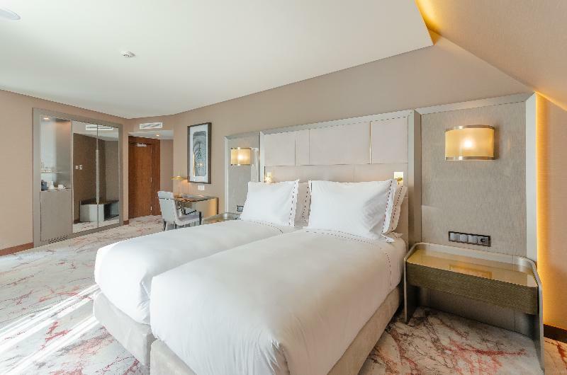 Turim Boulevard Hotel (Adults Only) Lisbona Esterno foto The photo shows a modern hotel room featuring two twin beds with white bedding, placed against a textured headboard. The room has a stylish and contemporary design, with soft lighting from wall sconces on either side of the beds. In the background, t