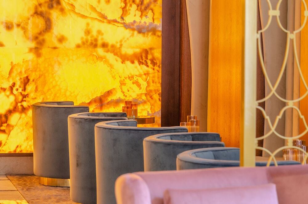 Turim Boulevard Hotel (Adults Only) Lisbona Esterno foto The photo features a stylish interior space, likely a lounge or bar area. In the foreground, there are soft, curved seating arrangements in a muted blue color. Behind them, there is a striking backdrop made of agate or a similar stone, glowing in war