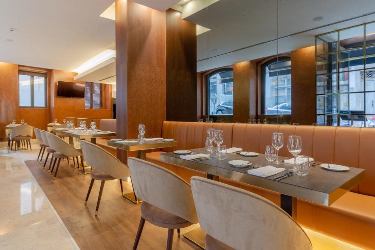 Turim Boulevard Hotel (Adults Only) Lisbona Esterno foto The photo shows a modern restaurant interior. The space features a combination of wooden and metallic elements, with a warm color scheme. There are several tables set for dining, each equipped with plates, glasses, and cutlery. The seating consists o