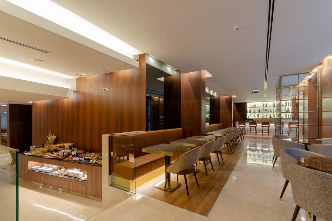 Turim Boulevard Hotel (Adults Only) Lisbona Esterno foto The photo shows a modern café or restaurant interior featuring a sleek design with wooden paneling and warm lighting. There are seating areas with large tables and stylish chairs. A buffet or display area is visible, showcasing an assortment of food 