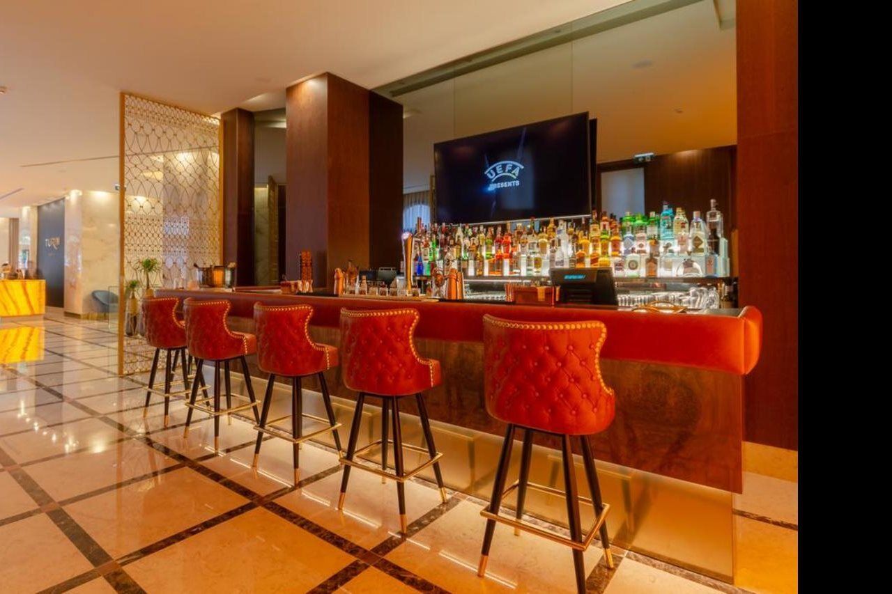 Turim Boulevard Hotel (Adults Only) Lisbona Esterno foto The photo shows an upscale bar area. There is a long bar counter with several red upholstered stools arranged in front of it. Behind the bar, a well-stocked selection of various alcoholic beverages is displayed on shelves, illuminated by soft lightin