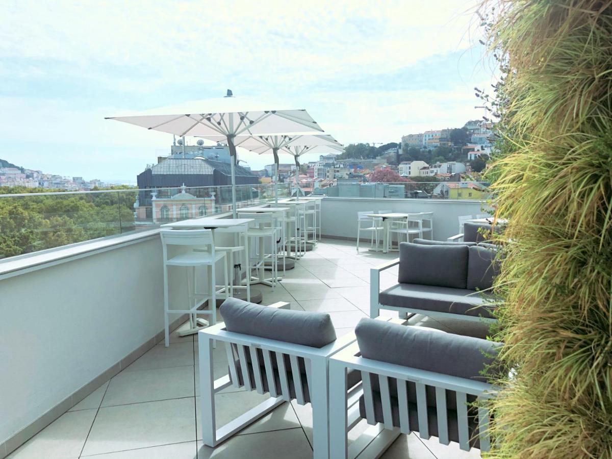 Turim Boulevard Hotel (Adults Only) Lisbona Esterno foto The photo depicts a rooftop terrace featuring modern outdoor furniture. There are several lounge chairs and small tables, complemented by large umbrellas for shade. In the background, you can see a cityscape with buildings and hills, indicating a nic